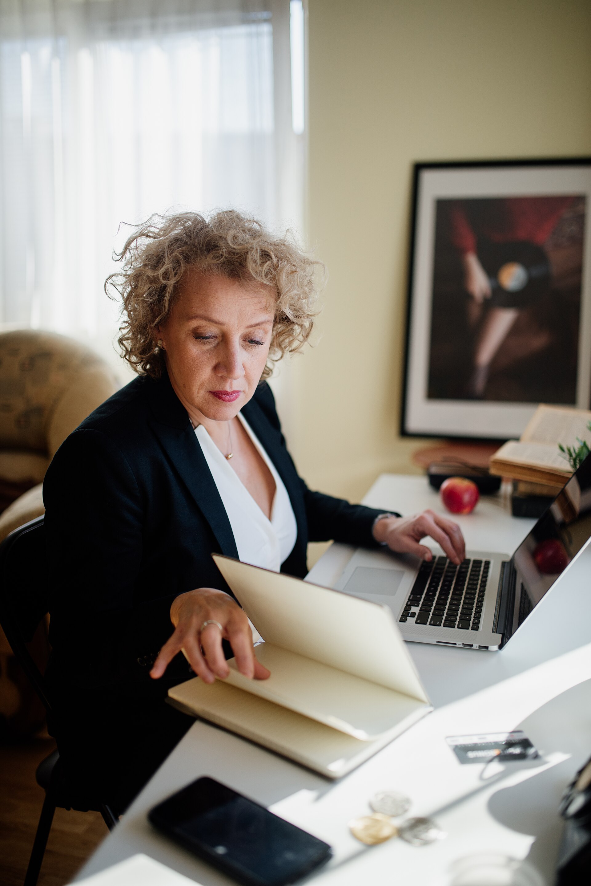 Smartphone and laptop used to scan and organize business paperwork on a desk